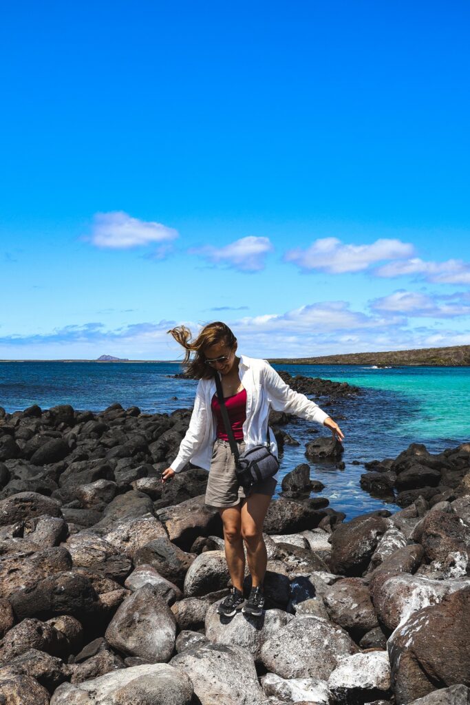 Kobieta stojąca na wulkanicznych kamieniach przy plaży na Wyspach Galapagos