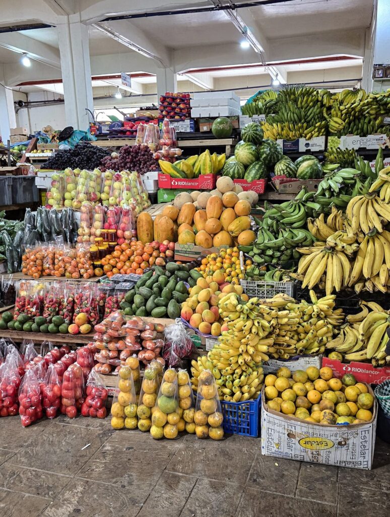 targ z wystawionymi owocami takimi jak banany, mango, jabłka, truskawki i arbuzy.